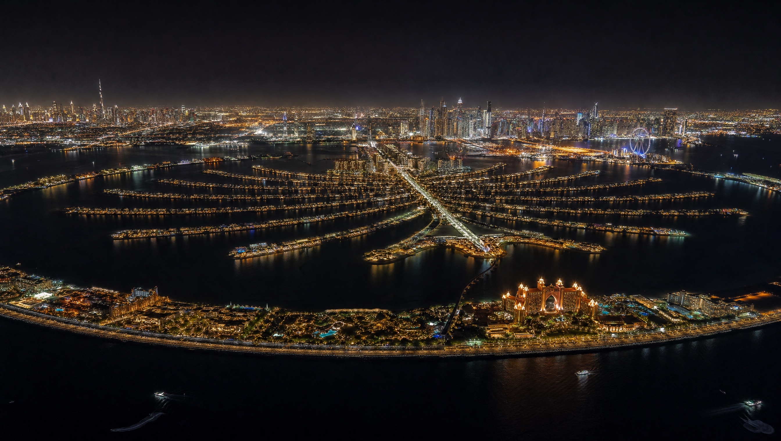 Palm Jumeirah at night from above the sea, Atlantis on the crescent and the Dubai Marina skyline behind
