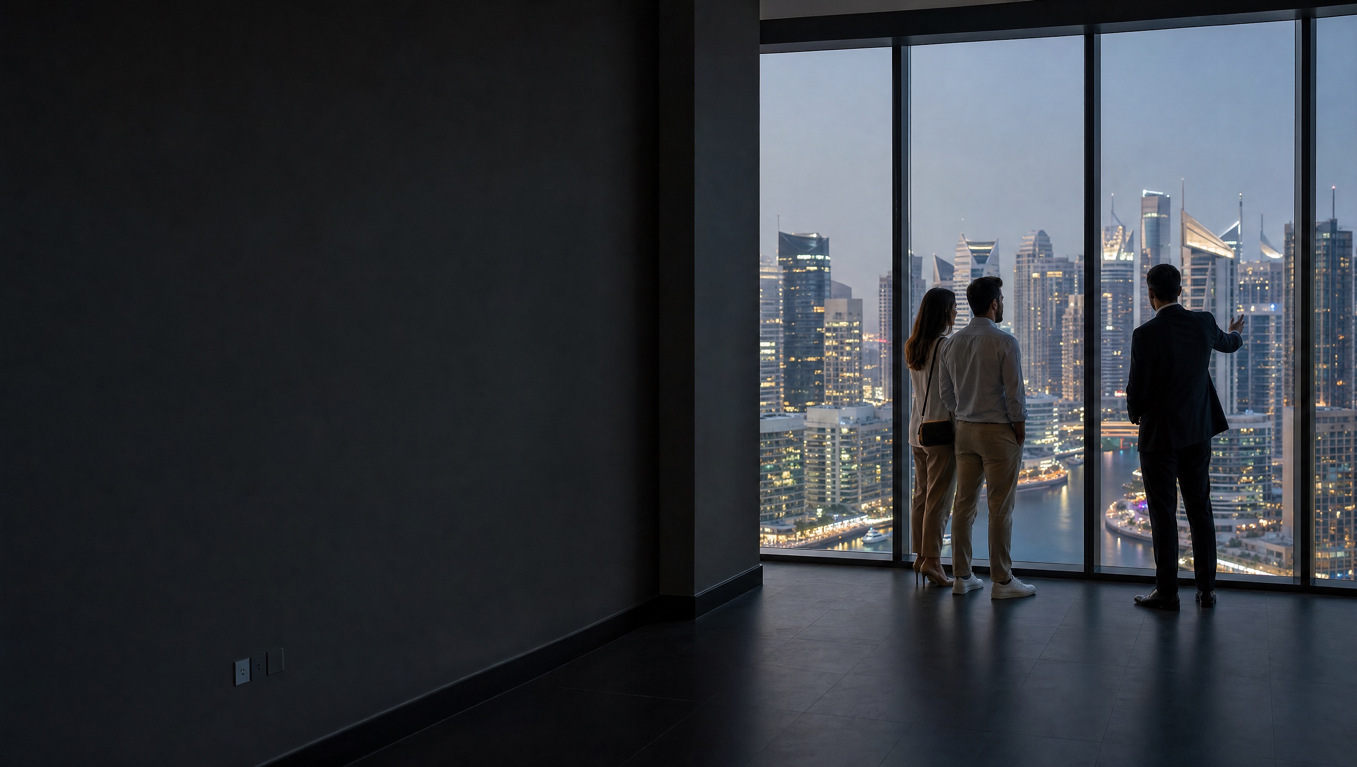 A broker shows a client an apartment at dusk, Dubai Marina below